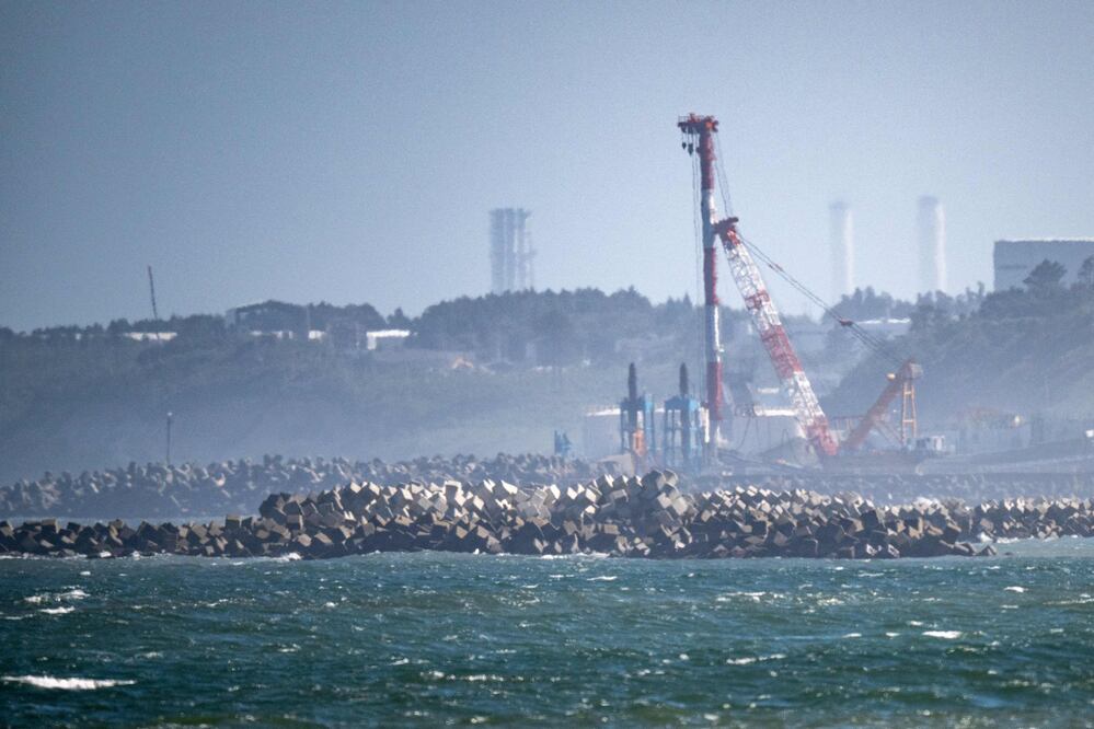 TOPSHOT - A general view shows the facilities of the Tokyo Electric Power Company's (TEPCO) crippled Fukushima Daiichi Nuclear Power Plant (back), as seen from Ukedo fishing port in Namie, Fukushima prefecture on August 24, 2023. Japan began releasing wastewater from the crippled Fukushima nuclear plant into the Pacific Ocean on August 24 despite angry opposition from China and local fishermen. (Photo by Philip FONG / AFP)