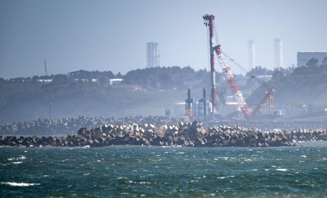 TOPSHOT - A general view shows the facilities of the Tokyo Electric Power Company's (TEPCO) crippled Fukushima Daiichi Nuclear Power Plant (back), as seen from Ukedo fishing port in Namie, Fukushima prefecture on August 24, 2023. Japan began releasing wastewater from the crippled Fukushima nuclear plant into the Pacific Ocean on August 24 despite angry opposition from China and local fishermen. (Photo by Philip FONG / AFP)