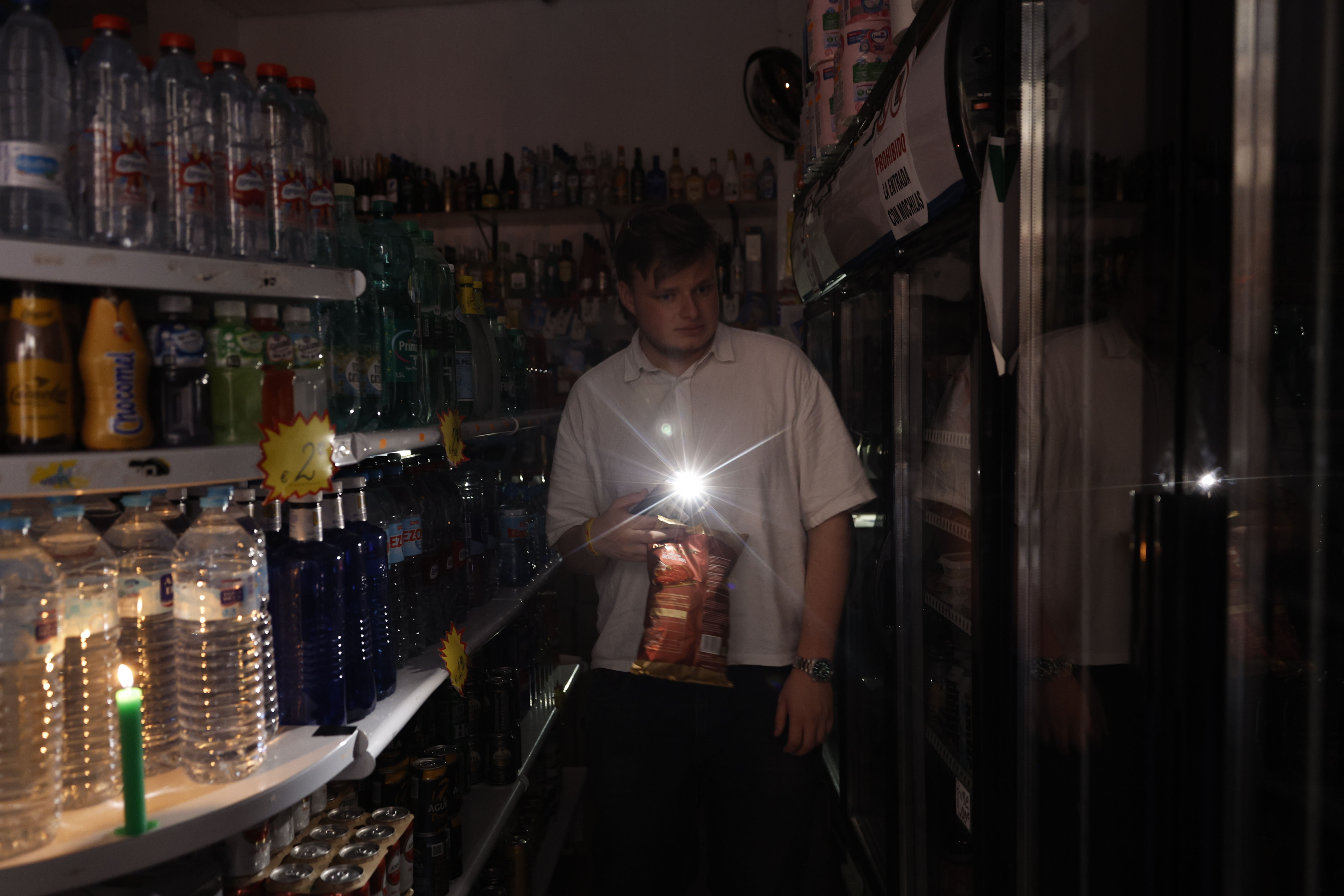 Una persona utiliza su teléfono móvil como linterna en un ultramarinos en Valencia, este lunes, con motivo del apagón de suministro eléctrico. Foto: EFE/ Biel Alino