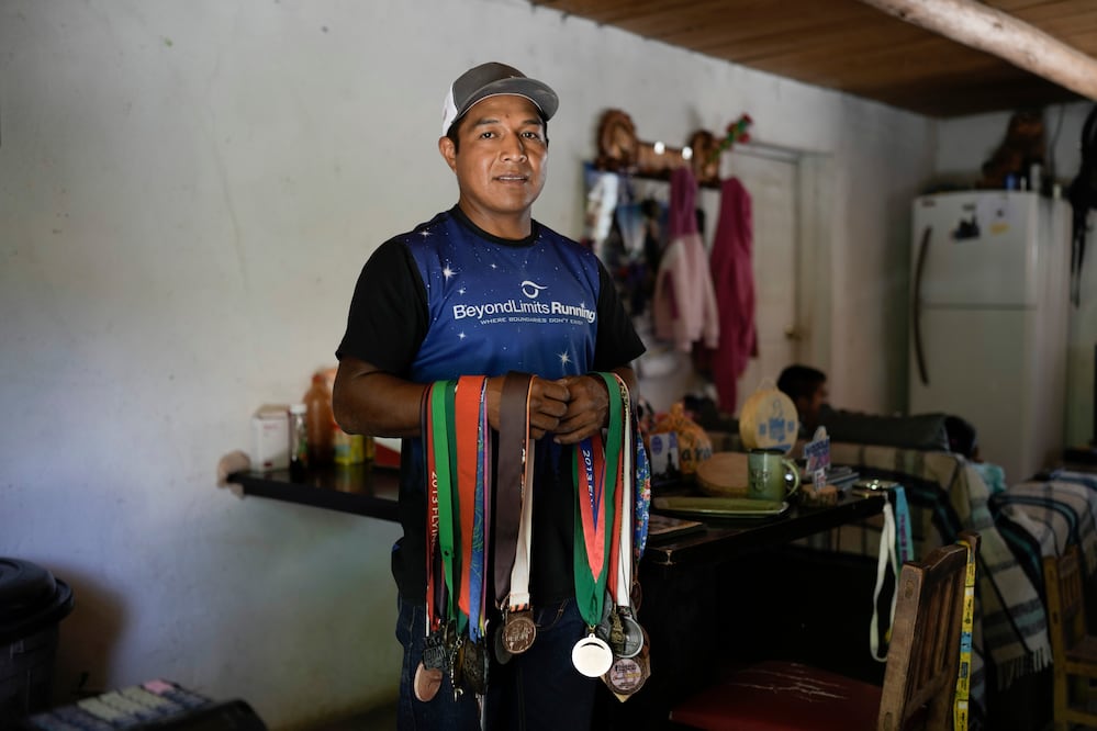 El ultramaratonista Miguel Lara posa para una fotografía con algunas de sus medallas en su casa en Porochi, una comunidad indígena en las remotas montañas Tarahumara del norte de México, el domingo 12 de mayo de 2024.. (AP Foto/Eduardo Verdugo)