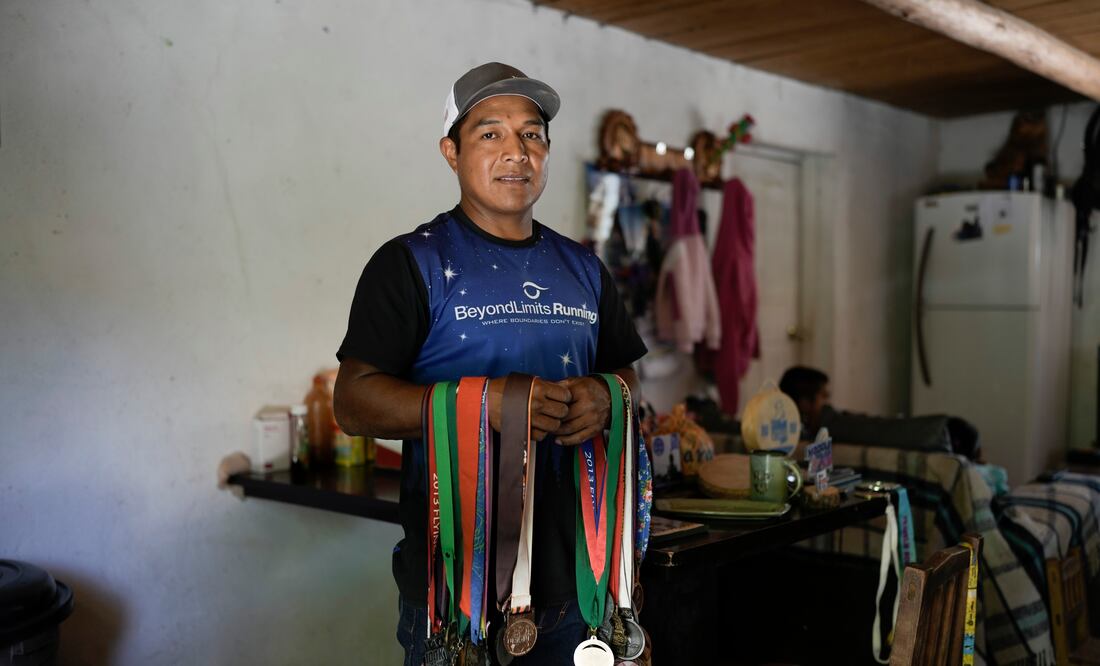 El ultramaratonista Miguel Lara posa para una fotografía con algunas de sus medallas en su casa en Porochi, una comunidad indígena en las remotas montañas Tarahumara del norte de México, el domingo 12 de mayo de 2024.. (AP Foto/Eduardo Verdugo)